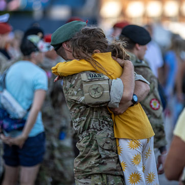 En mand i uniform løfter sin datter til et kram